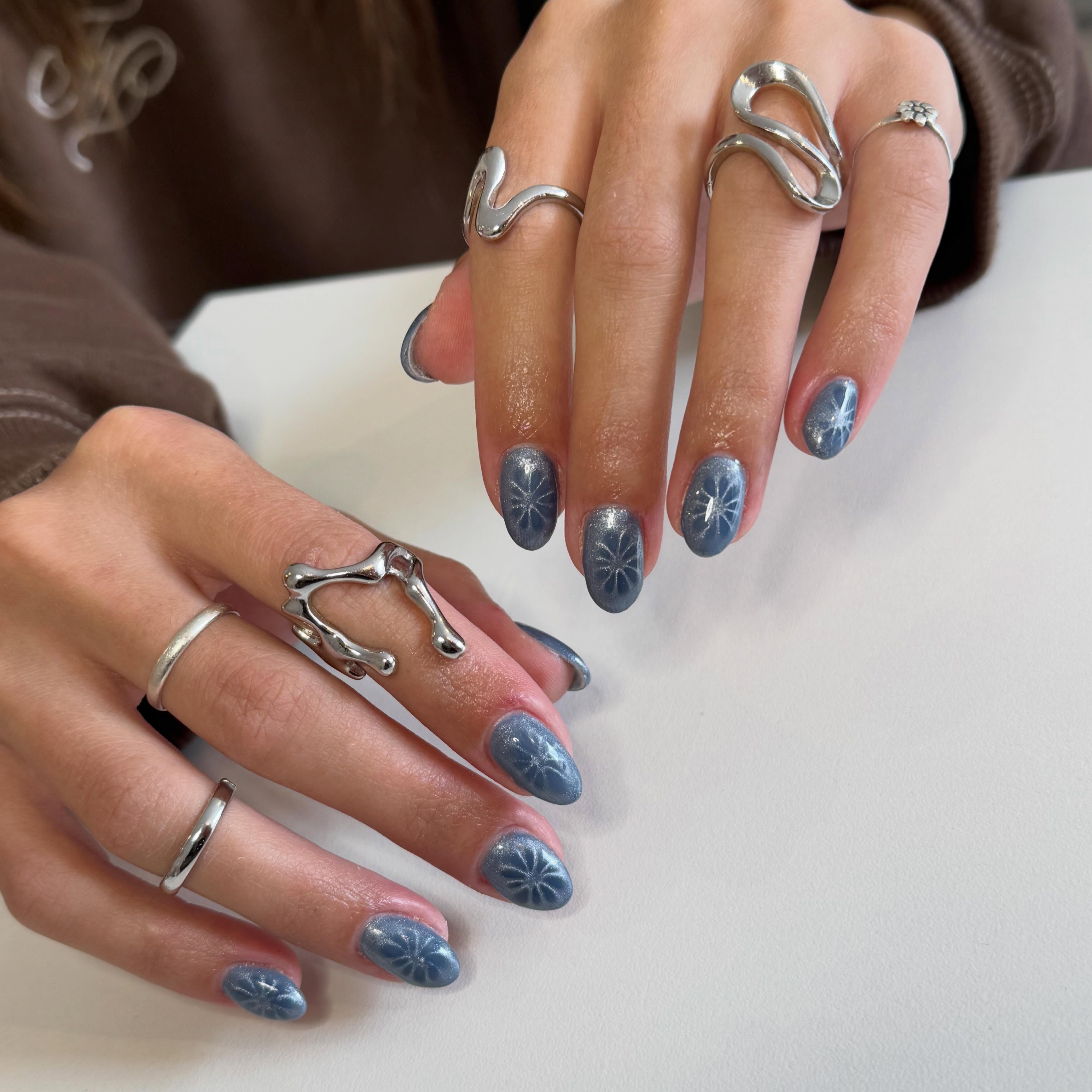 Diseño de uñas azul denim con efecto cat eye y detalles claros